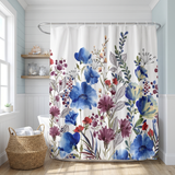 Floral shower curtain of blue, purple and red blooms in a bright white bathroom beside a tub and basket 