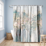 Abstract shower curtain of misty blossom trees in blush and teal in a blue bathroom beside a freestanding tub and basket 