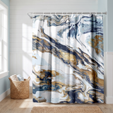 Abstract shower curtain of navy, gold and white marbled swirls in a bright white bathroom beside a tub and basket 