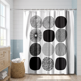 Abstract shower curtain of black and white patterned circles in a bright white bathroom beside a tub and basket 