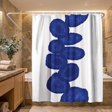 Shower curtain with a column of deep navy ink blots on white in a wood and stone bathroom beside folded towels 