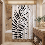 Shower curtain with a bold black palm frond on pale stripes in a wood and stone bathroom beside folded towels 