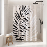 Shower curtain with a bold black palm frond on pale stripes in a walk-in shower beside a black rain head and stool 