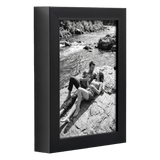 Angled black 5x7 deep frame, a couple sitting on rocks beside a river 