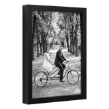 Angled black 8x12 deep frame, a bride and groom riding a tandem bicycle 