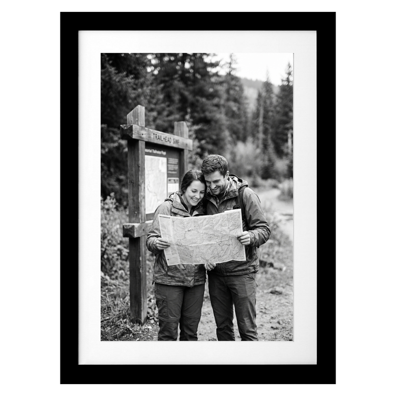 Black Streamline frame, 5x7, with a white mat, holding a photo of a couple reading a map by a trail sign #flat
