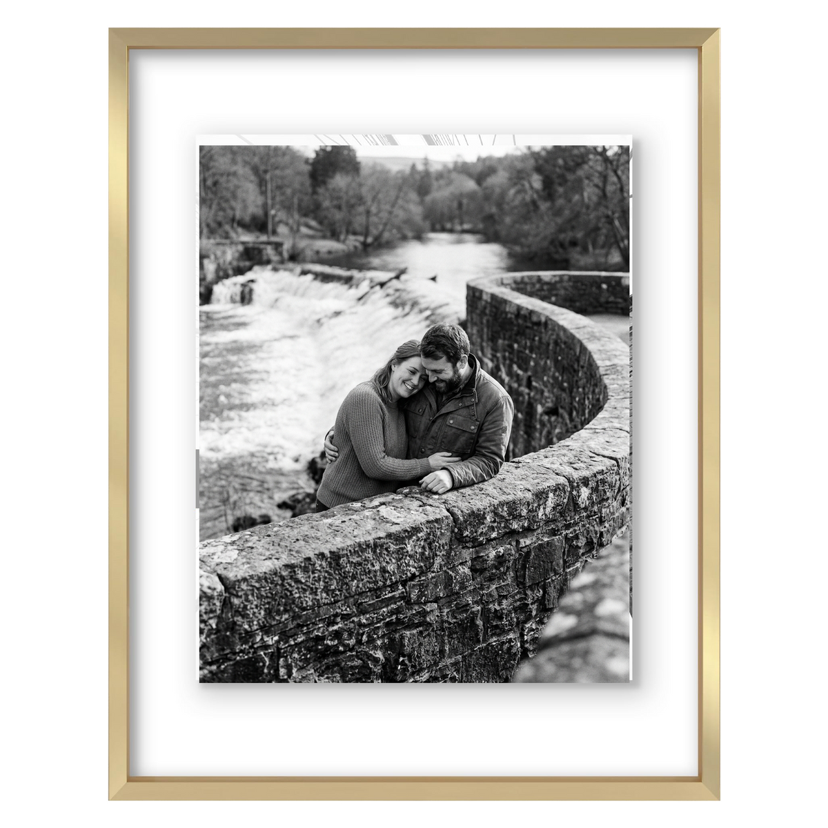 Gold metal float frame, a couple seated on a stone bridge above a weir 
