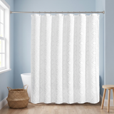 White woven linen shower curtain tufted with a diamond pattern in a blue bathroom beside a freestanding tub and basket 
