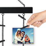 A hand clipping a photo onto one of the display's black metal chains 