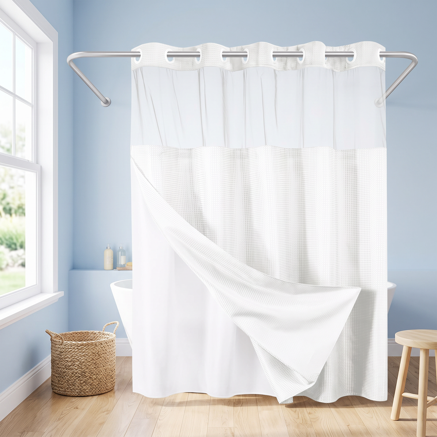 A white shower curtain with a textured waffle-weave lower half and a smooth upper panel, hanging from a silver rod in a light blue bathroom with a window, woven basket, and wooden stool. 