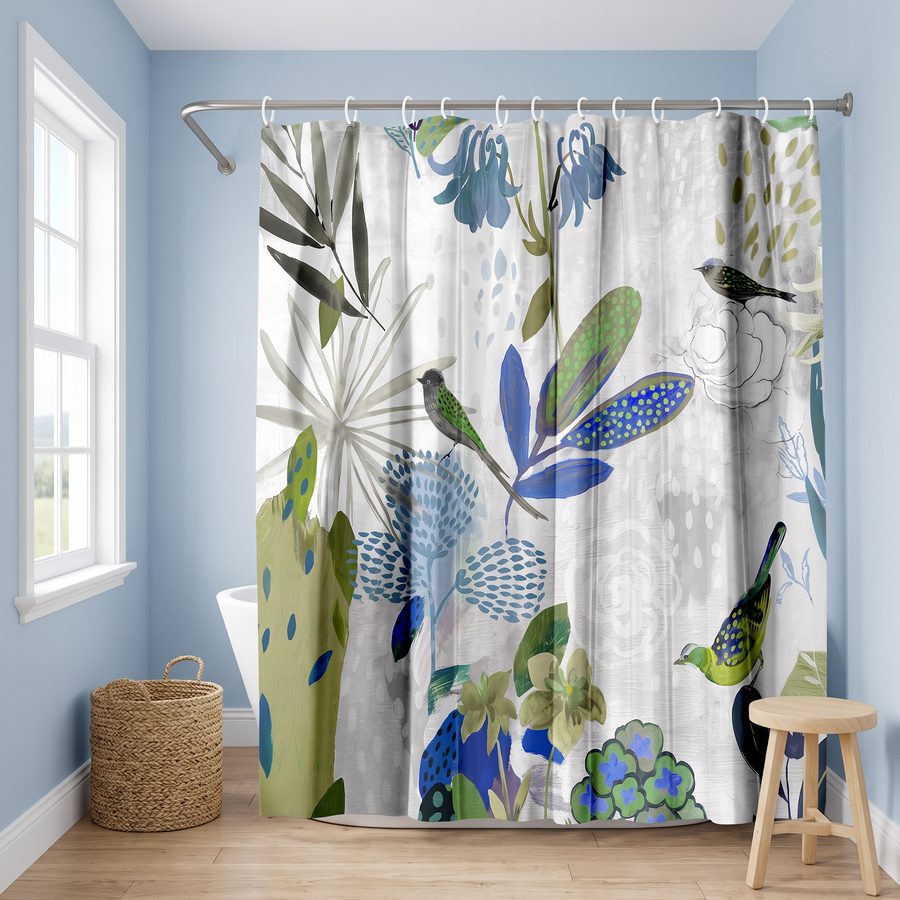A shower curtain with a botanical and bird pattern hangs in a bathroom setting with light blue walls, a window, a wicker basket, and a wooden stool. 