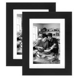 Two black Signature frames with white mats, holding a photo of a couple baking a cake 