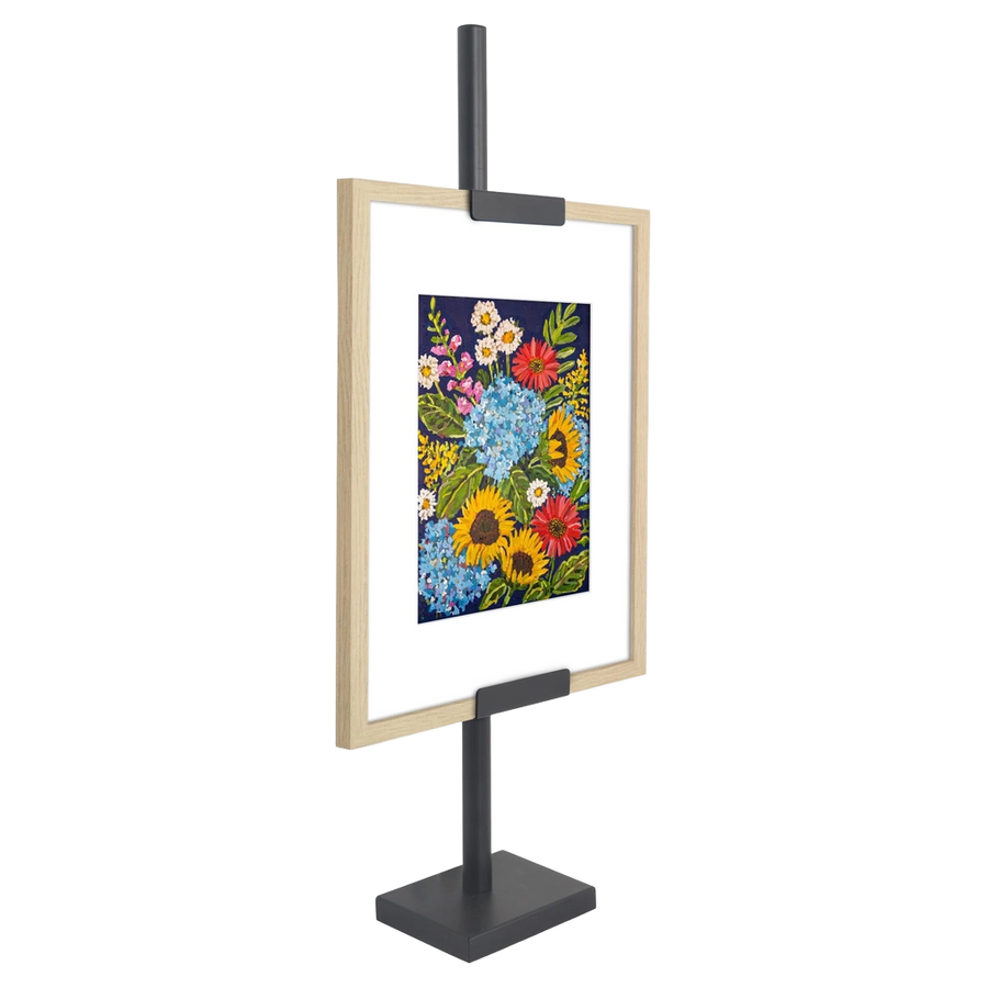Black adjustable easel stand gripping a light wood frame with a floral print #flat