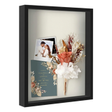 Black 16x20 shadow box holding a wedding photo, dried flowers and an invitation 