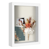 White 8.5x11 shadow box holding a wedding photo, dried flowers and an invitation 