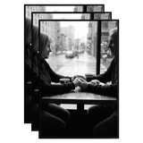 Three stacked black 20x30 Fusion frames all holding the same photo of a couple at a cafe window 