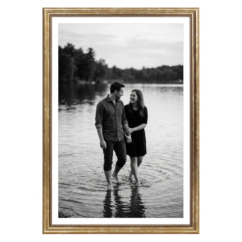 Gold beaded Heirloom frame, 12x18, holding a black-and-white photo of a couple wading in a lake