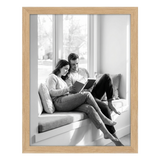 Natural oak Epic poster frame, 16x20, no mat, holding a black-and-white photo of a couple reading on a window seat 