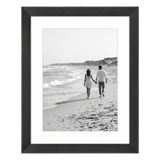 Black Hudson frame, 12x15, with a 9x12 white mat, holding a black-and-white photo of a couple walking a wide beach 