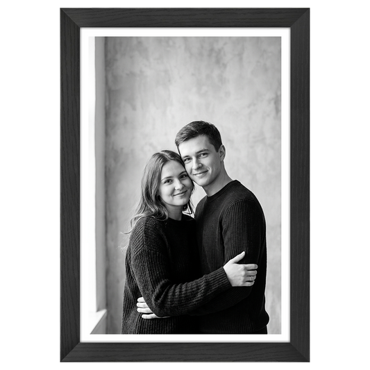 Black Hudson frame, 12x18, with an 11x17 white mat, holding a black-and-white studio portrait of a couple embracing #flat