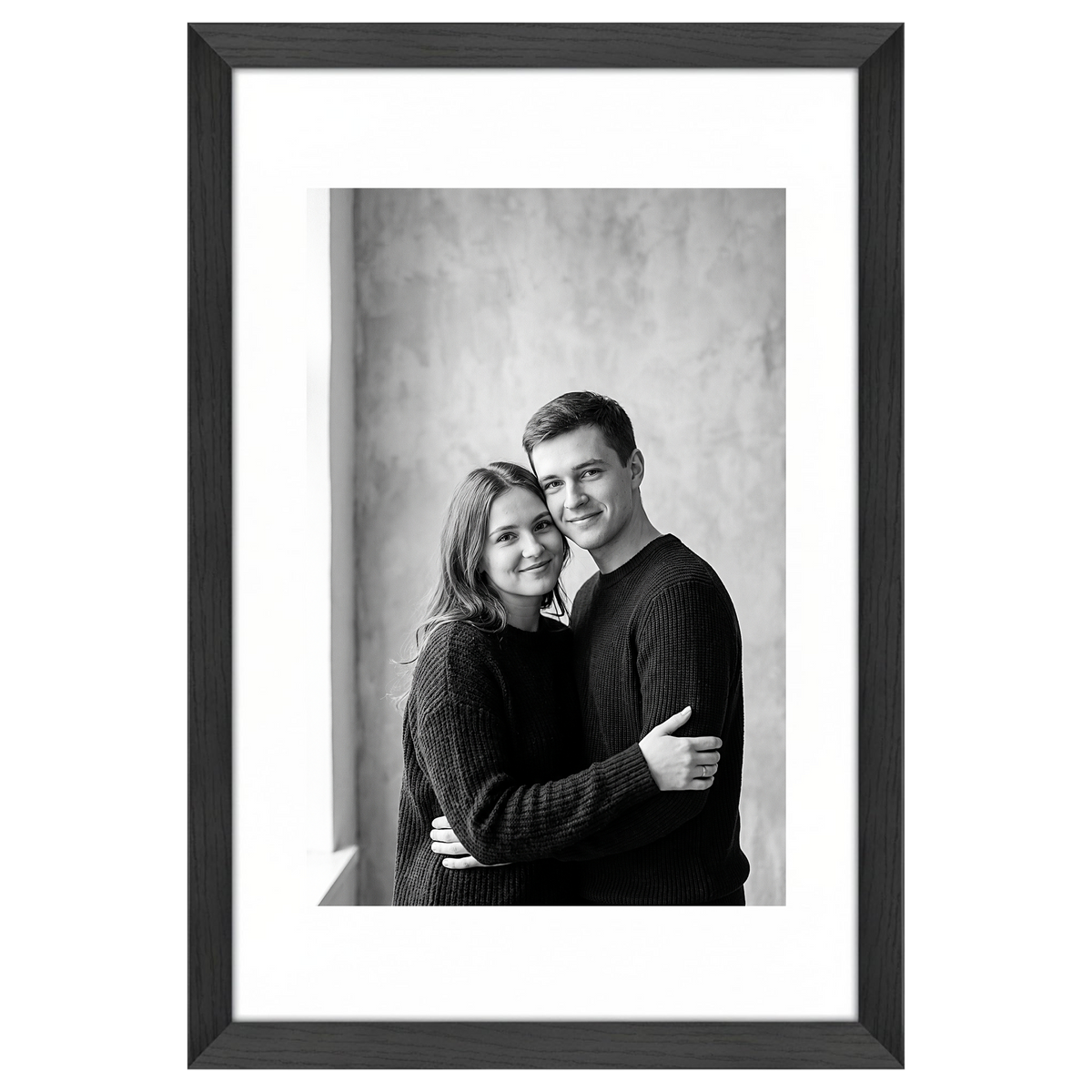 Black Hudson frame, 16x24, with a 12x18 white mat, holding a black-and-white studio portrait of a couple embracing 