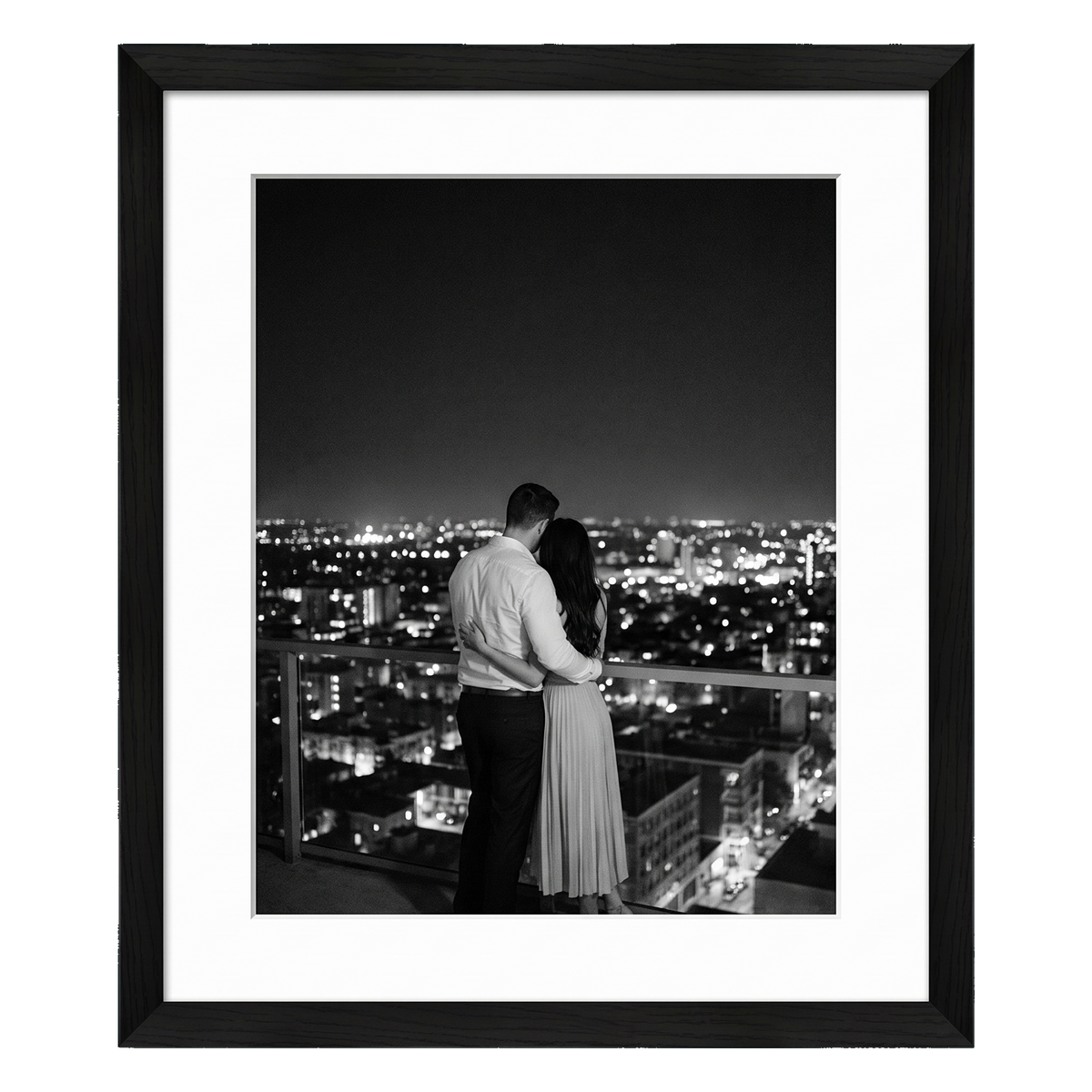 Black Hudson frame, 18x24, with a 12x18 white mat, holding a black-and-white photo of a couple above city lights at night 
