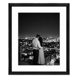 Black Hudson frame, 18x24, with a 12x18 white mat, holding a black-and-white photo of a couple above city lights at night 