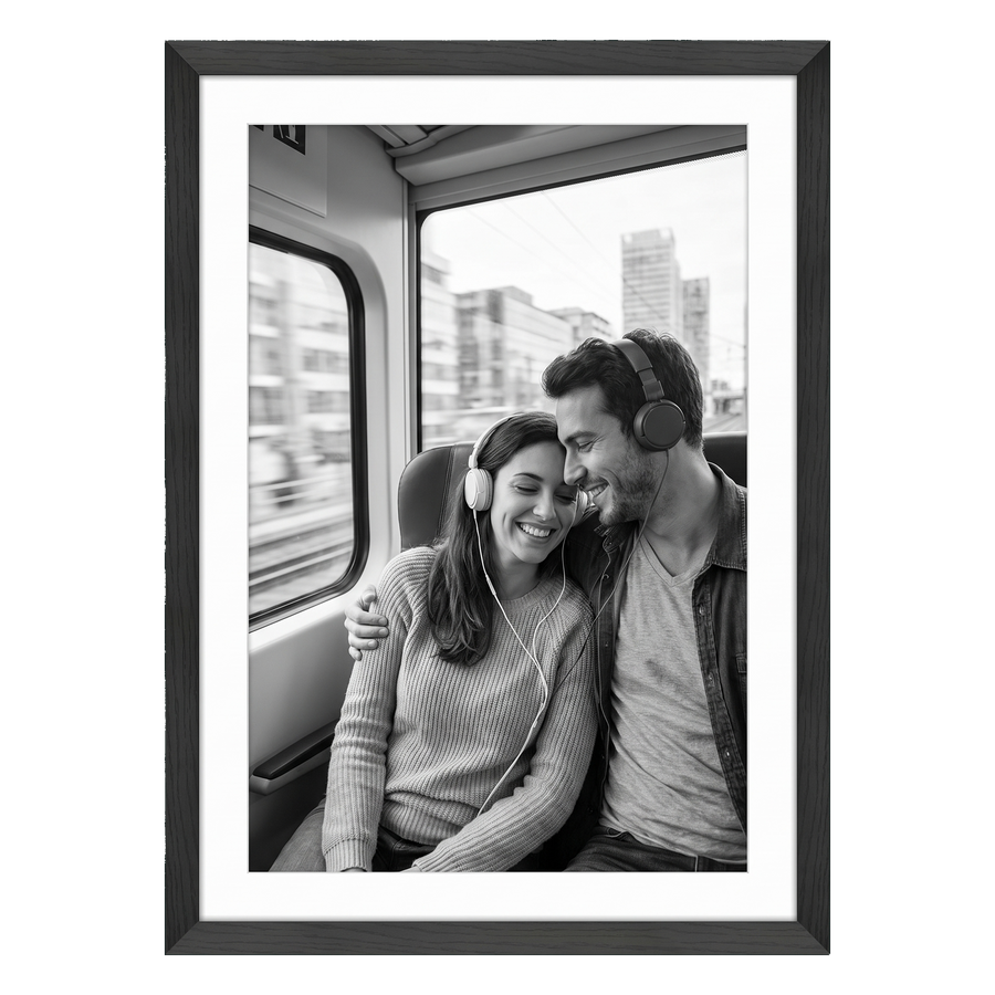 Black Hudson frame, 24x34, with a 20x30 white mat, holding a black-and-white photo of a couple with headphones on a train 