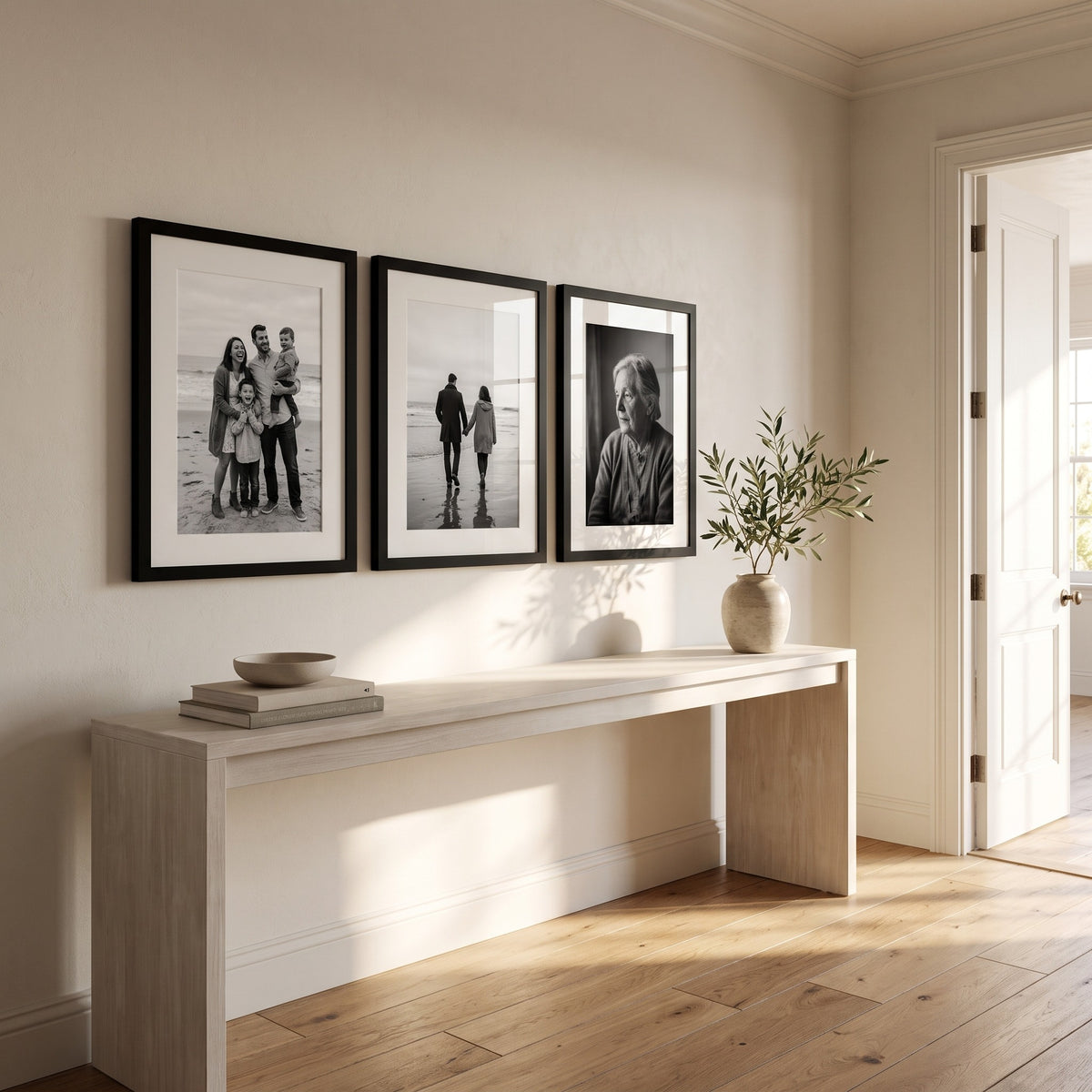 Three black 16x22 matted frames hung in a row above a console in a sunlit entry hall 