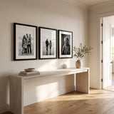 Three black 16x22 matted frames hung in a row above a console in a sunlit entry hall 