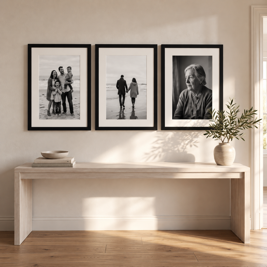 Front view of three matching black 16x22 frames with white mats and black-and-white family photos above a pale wood console 