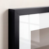 Close-up of a frame corner showing the mitred black moulding, white mat bevel and plexiglass glazing