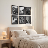 Six black picture frames in a grid above a bed in a calm bedroom 