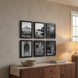 Six black picture frames in a grid above a walnut sideboard in a dining area 