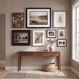Entryway with the eight-frame warm collected gallery wall hung above a walnut console table