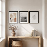 Three black 14x20 matted frames hung in a row above an oak console in an entry hall 