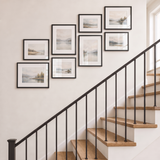Clustered eight-frame black gallery wall on a staircase, all frames matted and glazed
