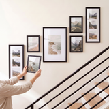 Hanging the last unmatted 8x10 to complete the ascending stairway gallery wall