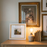 Evening vignette — gold 12x18 and white 11x14 Heirloom frames in warm lamp light 