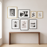 Seven Brooklyn aluminium frames in gold and black above a walnut console — three gold, four black, all matted 