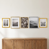 Five frames in brass, nickel and gold in one row above an oak sideboard 