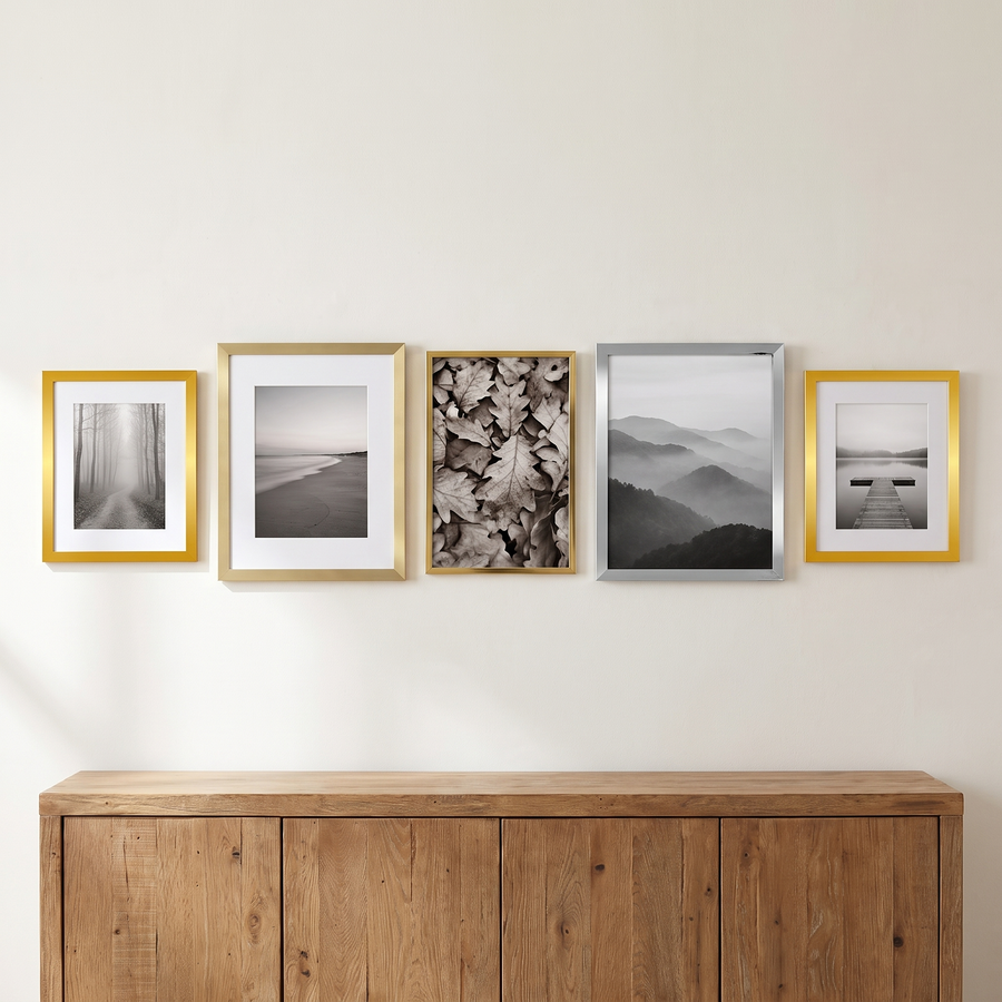 Five frames in brass, nickel and gold in one row above an oak sideboard #flat