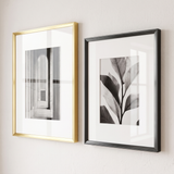 Close detail — polished gold beside graphite-black aluminium, slim flat profile, wide white mats 