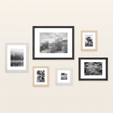 Six-frame gallery wall in black, white and natural oak on a warm off-white wall 