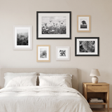 The six-frame set hung above a bed with white linen bedding 