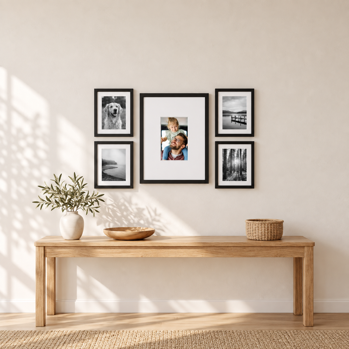 Digital gallery wall of five above an oak console — the digital picture frame centred with its small colour screen in a deep white mat, surrounded by four matted black 9x12 frames with black-and-white photographs 