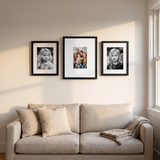 The three-frame digital set styled above a linen sofa in a living room, the digital frame's small colour screen centred between two black-and-white portraits 