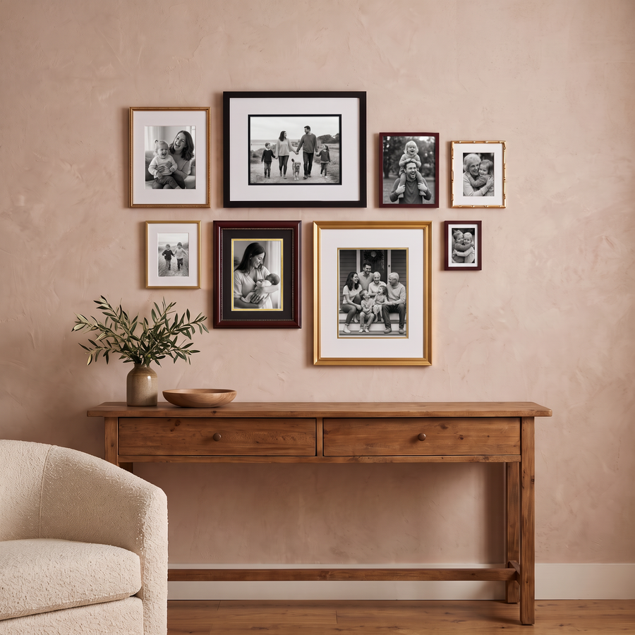 Warm Collected Eight: eight frames in black, mahogany and gold around a black and a gold Veranda 16x20. Shown in a warm, softly lit living room, above a rustic warm-wood console table, with family photos in the frames 