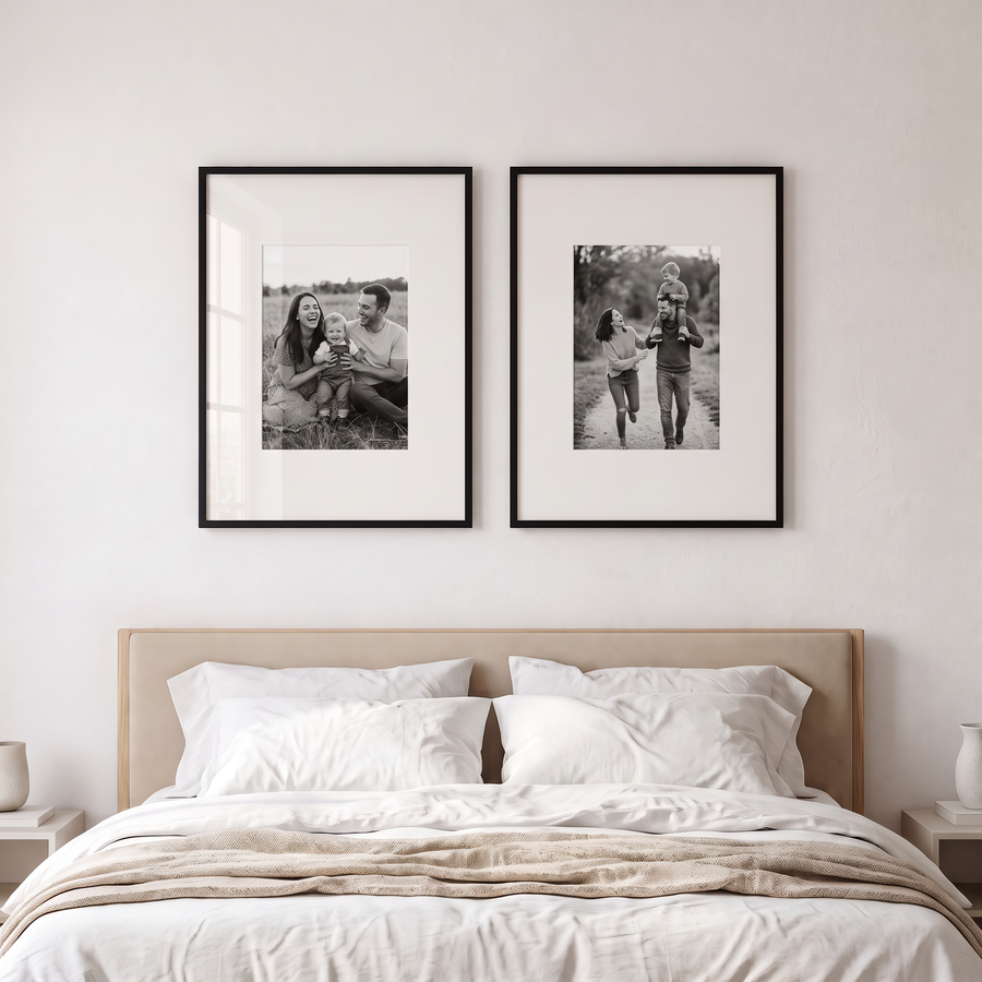 Wide Mat Pair 22x28: two black Streamline 22x28 frames with 12x16 mats, hung side by side. Shown in a modern bedroom, above a king bed with white linen, with family photos in the frames 