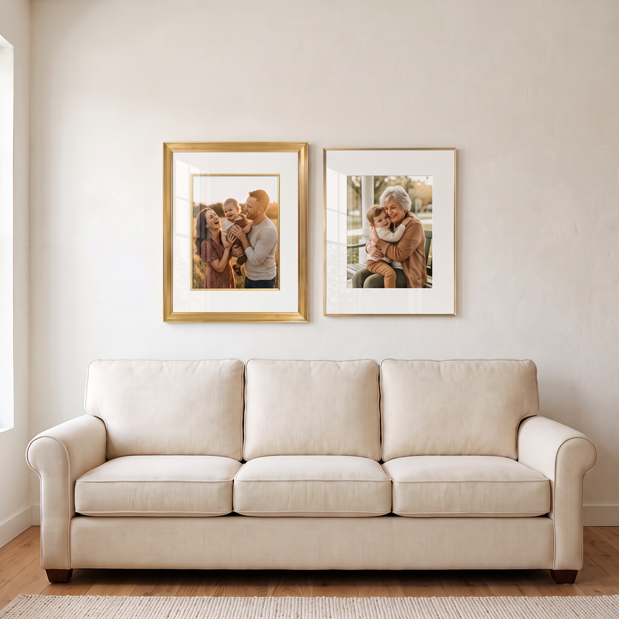 Gilded Pair: two gold 16x20 frames matted to 11x14, a Veranda and a Brooklyn, side by side. Shown in a bright living room, above a cream sofa, with family photos in the frames 